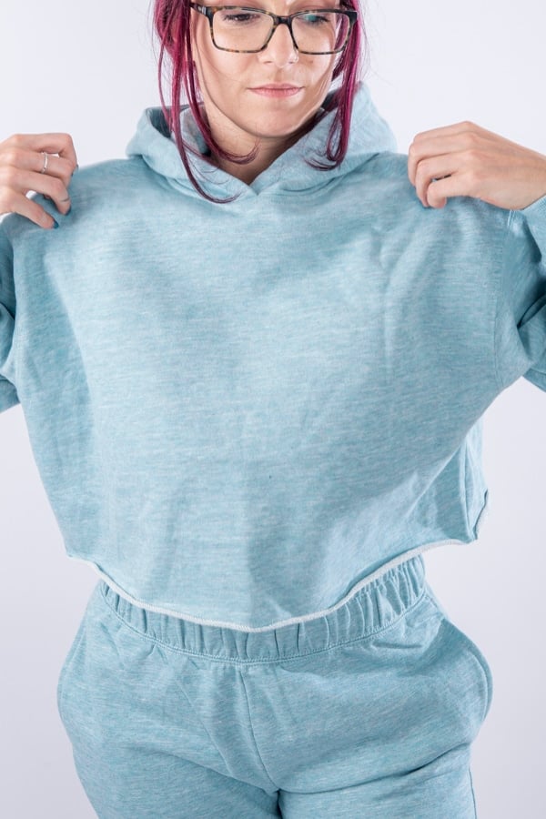 Femme vue de face portant un sweatshirt court en french terry de couleur vert menthe avec capuche.