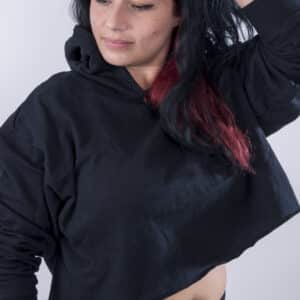 Femme vue de face portant un sweatshirt court en french terry de couleur noir avec capuche.