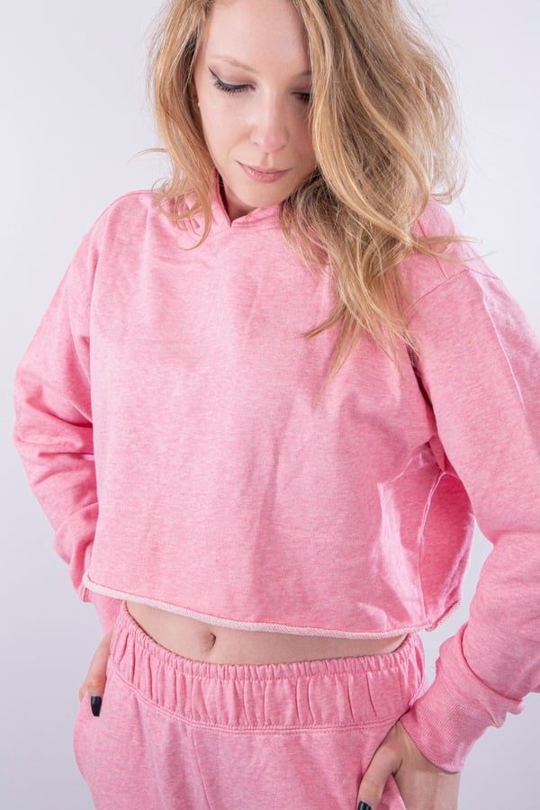 Femme vue de face portant un sweatshirt court en french terry de couleur rose avec capuche.