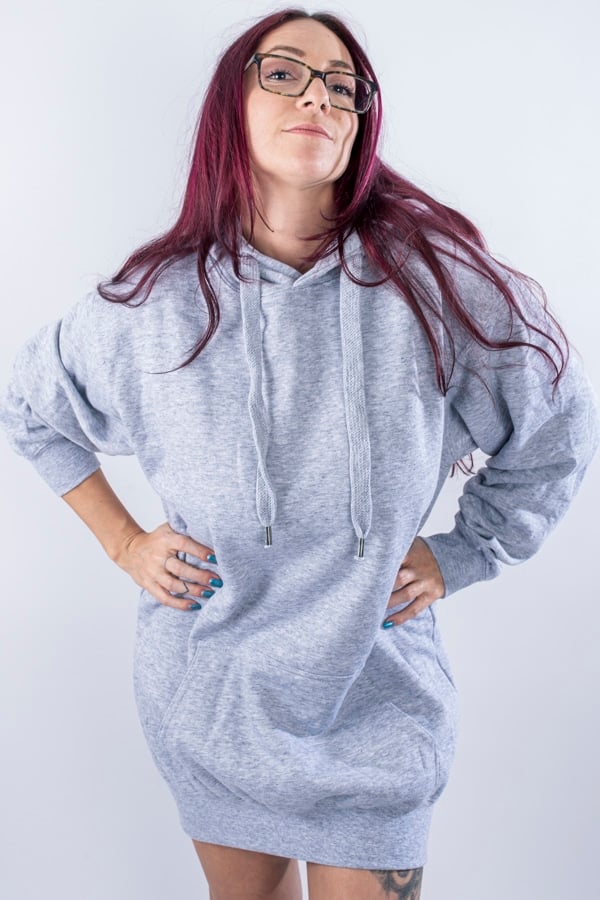 Femme vue de face portant un sweatshirt oversize en fleece de couleur gris avec capuche et poche kangourou.