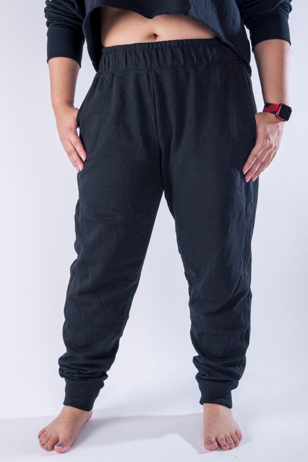Femme vue de face portant un jogging en french terry de couleur noir avec des poches.