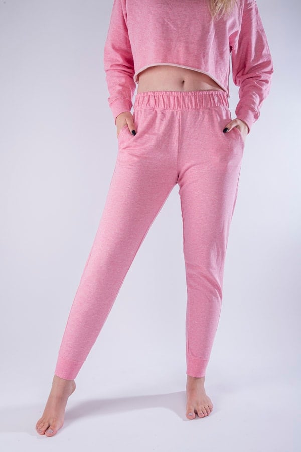 Femme vue de face portant un jogging en french terry de couleur rose avec des poches.