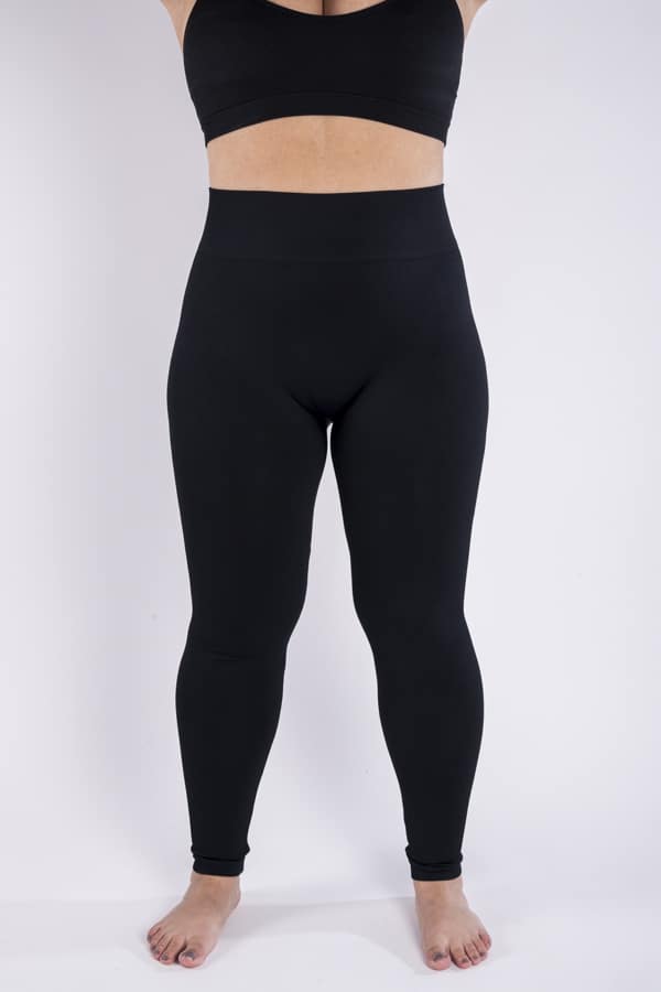 Femme vue de face qui porte un legging noir en taille unique. Coupe seamless