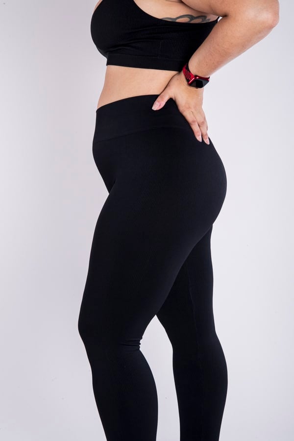 Femme vue de profil qui porte un legging noir en taille unique. Coupe seamless