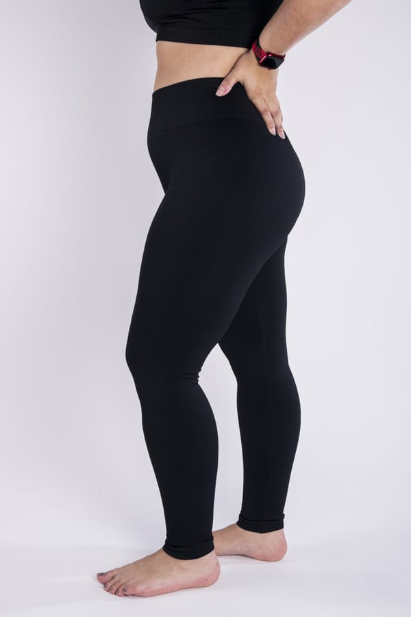 Femme vue de profil qui porte un legging noir en taille unique. Coupe seamless