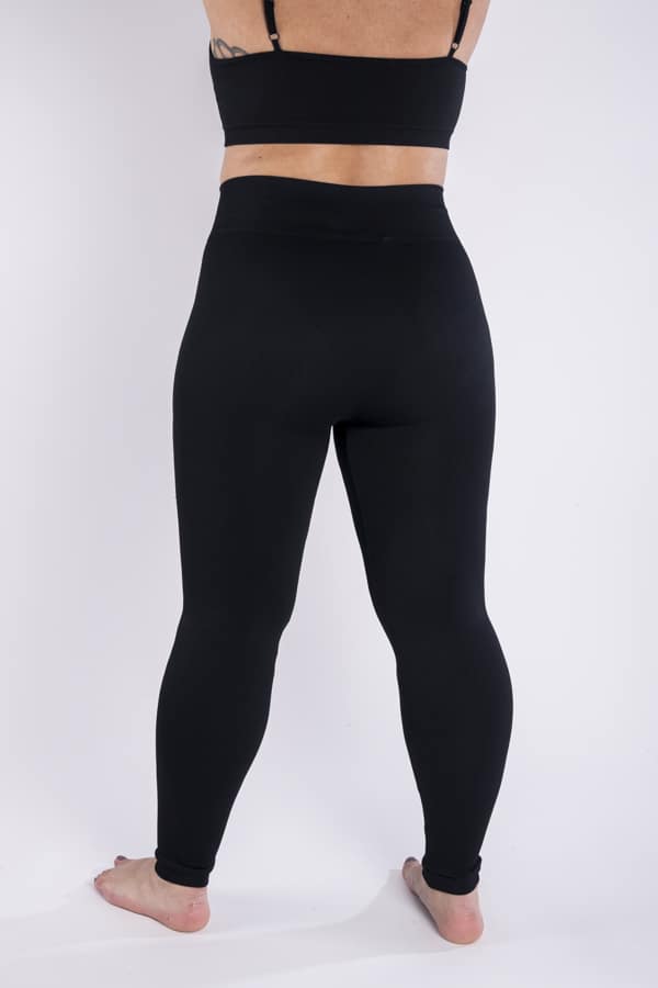 Femme vue de dos qui porte un legging noir en taille unique. Coupe seamless