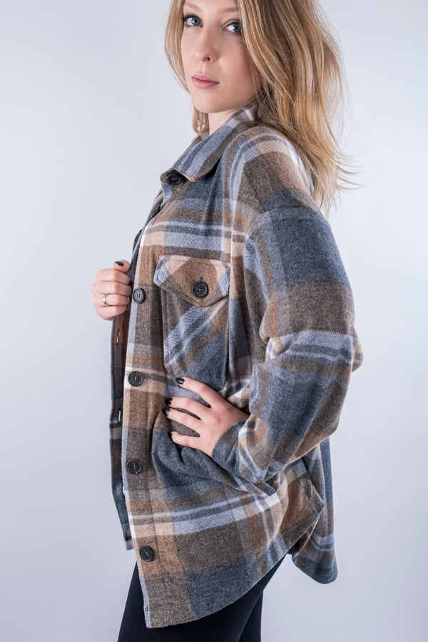 Femme vue de profil portant une veste en plaid de couleur brune avec des poches avants et latérales. Fermeture par boutons à l'avant.