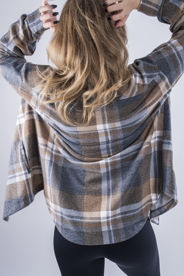 Femme vue de dos portant une veste en plaid de couleur brune avec des poches avants et latérales. Fermeture par boutons à l'avant.