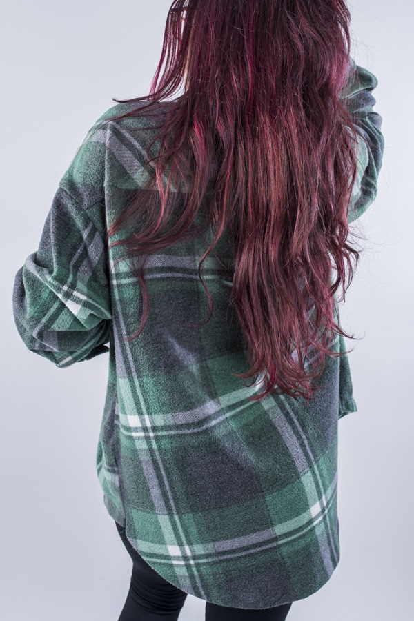 Femme vue de dos portant une veste en plaid de couleur vert forêt avec des poches avants et latérales. Fermeture par boutons à l'avant.
