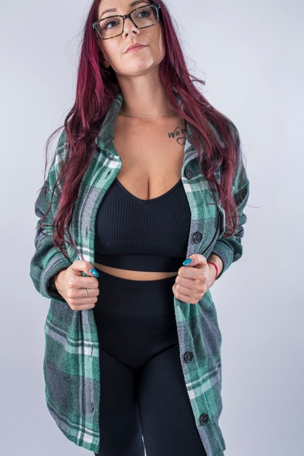 Femme vue de face portant une veste en plaid de couleur vert forêt avec des poches avants et latérales. Fermeture par boutons à l'avant.
