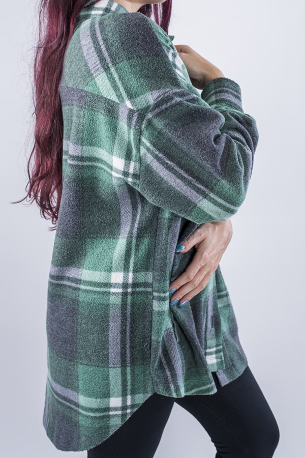 Femme vue de profil portant une veste en plaid de couleur vert forêt avec des poches avants et latérales. Fermeture par boutons à l'avant.